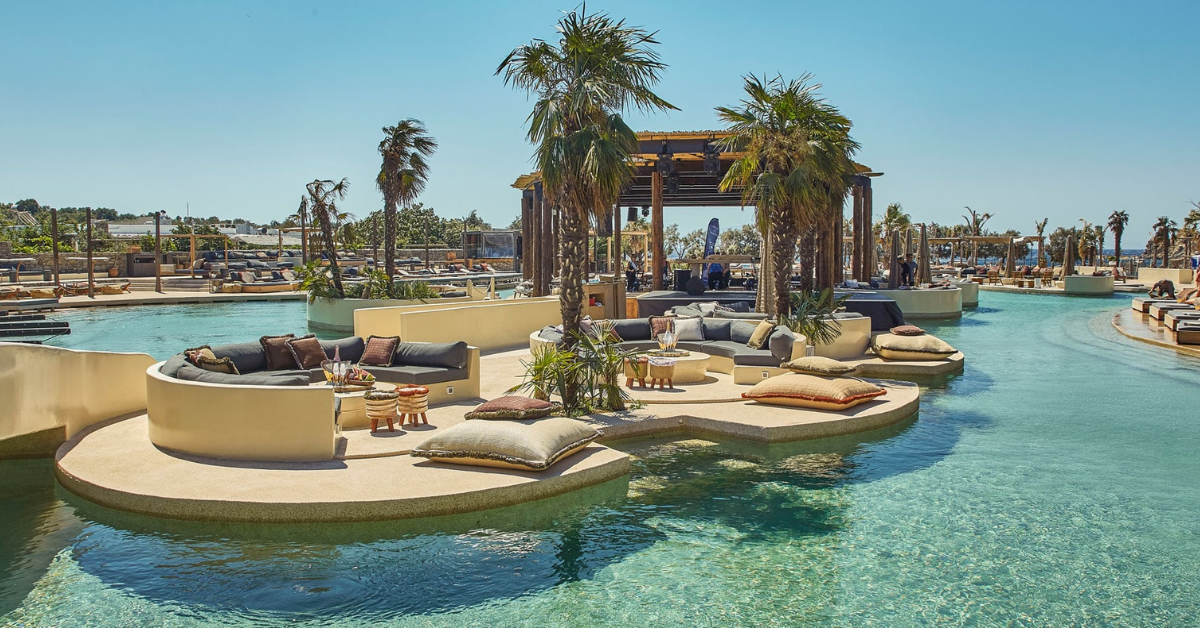 SantAnna Mykonos luxury beach club pool lounge with palm trees, VIP seating, sunbeds, and elegant summer party atmosphere in Mykonos 2026