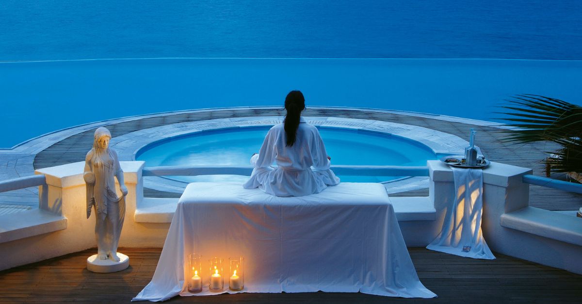 Luxury concierge professional in tailored suit overlooking Mykonos coastline, representing ultra-high-net-worth travel planning, bespoke villa coordination, and high-level relationship-driven concierge services.